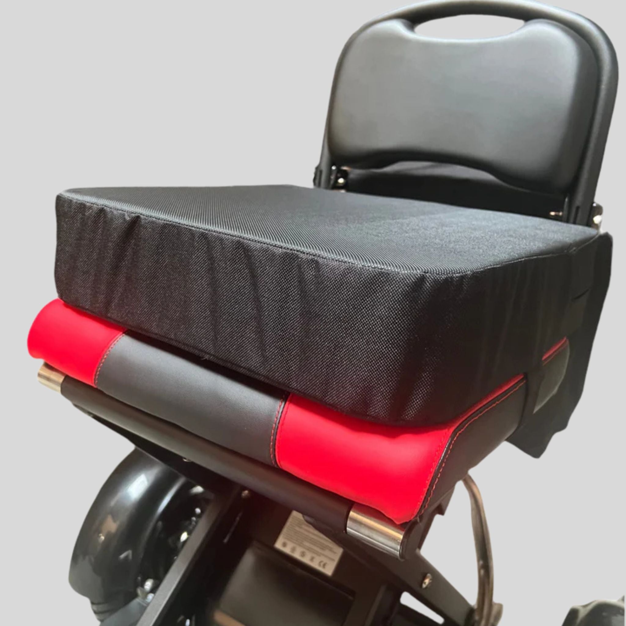 Ein schwarzer und roter gepolsterter Rollstuhlsitz mit einem dicken schwarzen Sitzpolster und einer schwarzen Rückenlehne, dargestellt vor einem weißen Hintergrund.