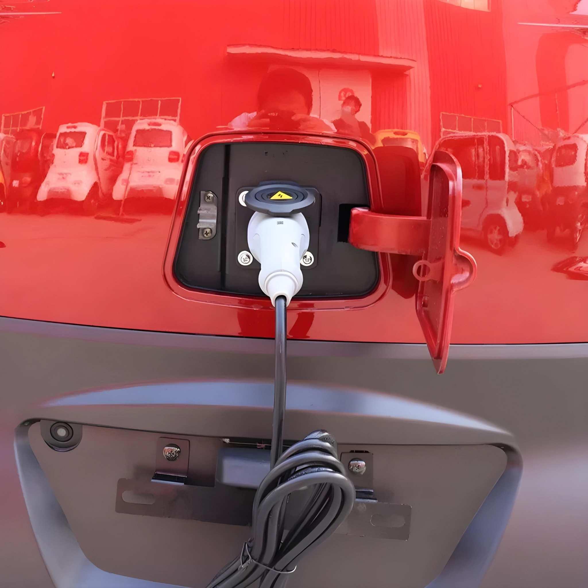 Nahaufnahme eines EQ-Mobil Kabinenrollers Lima Q3 Li 45 / 25 km/h (Lithium Akku, aktuelles Modell) mit eingestecktem Kabel; Spiegelungen von Menschen und geparkten Fahrzeugen im Hintergrund veranschaulichen die moderne Stadtmobilität.