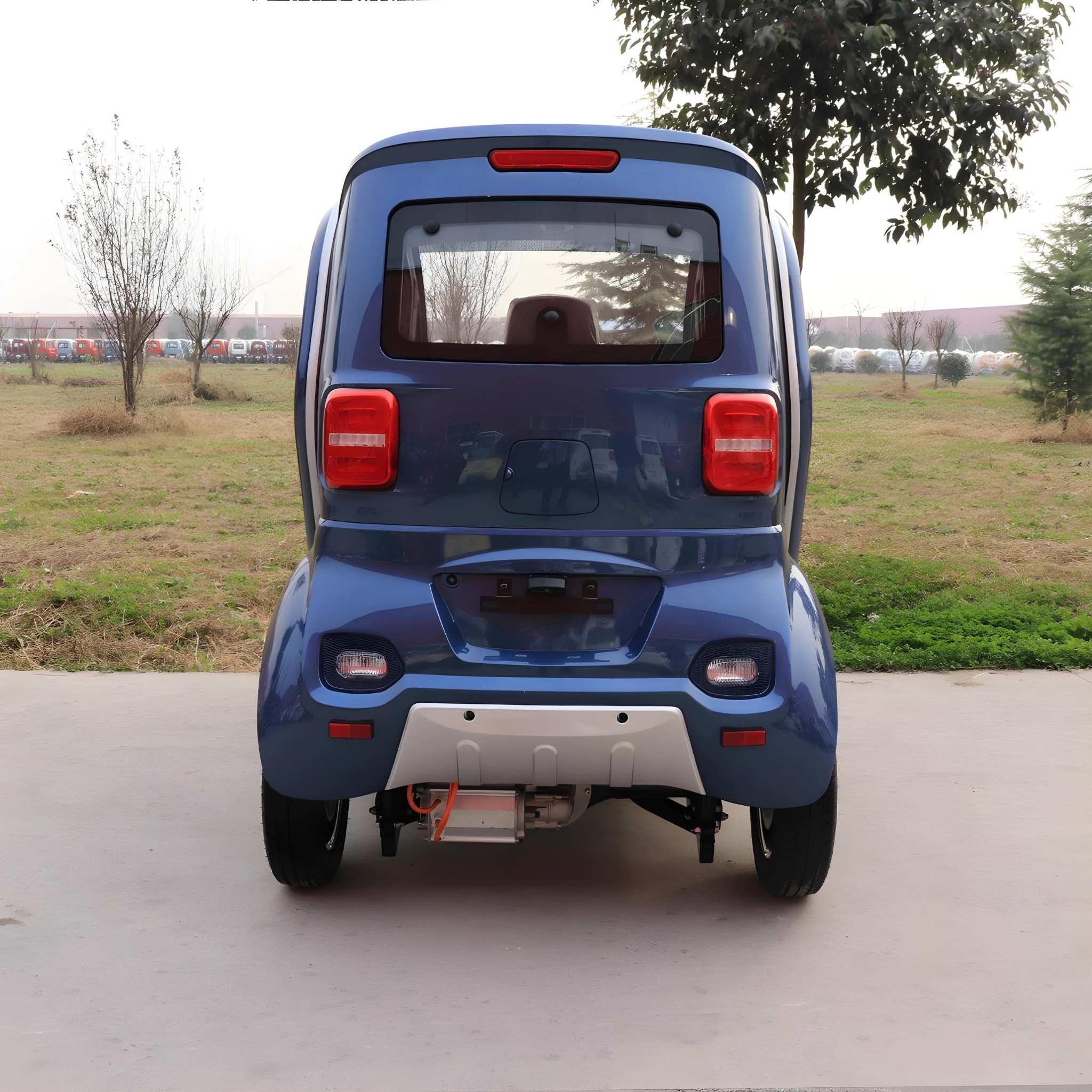 Ein kompakter blauer EQ-Mobil Kabinenroller Lima Q3 Li 45/25 km/h mit Lithium-Akku wird von hinten gezeigt, geparkt auf Beton mit einer Wiese und Bäumen im Hintergrund.