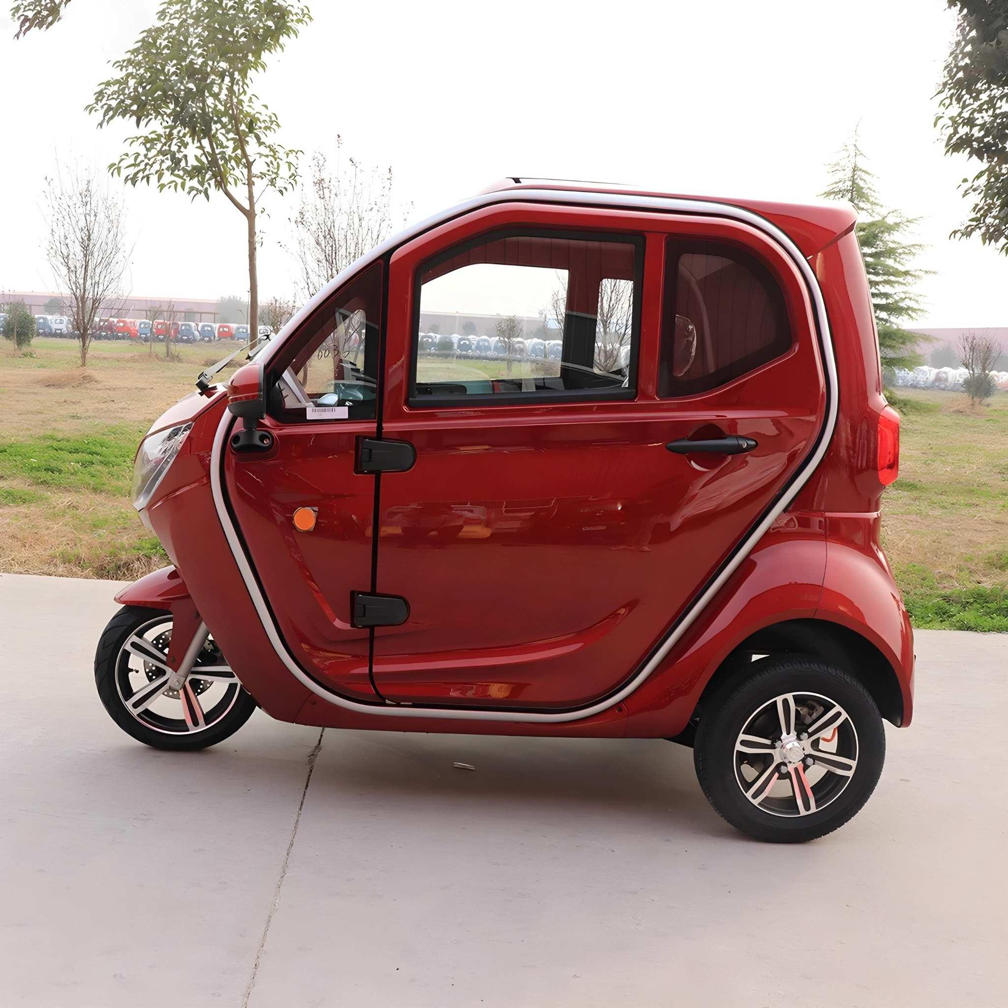 Ein kompakter, roter EQ-Mobil Kabinenroller Lima Q3 Li 45 / 25 km/h mit einem Lithium-Akku steht auf dem Bürgersteig in der Nähe von Gras und Bäumen unter einem bewölkten Himmel. Das aktuelle Modell hat zwei Türen und silberne Felgen.