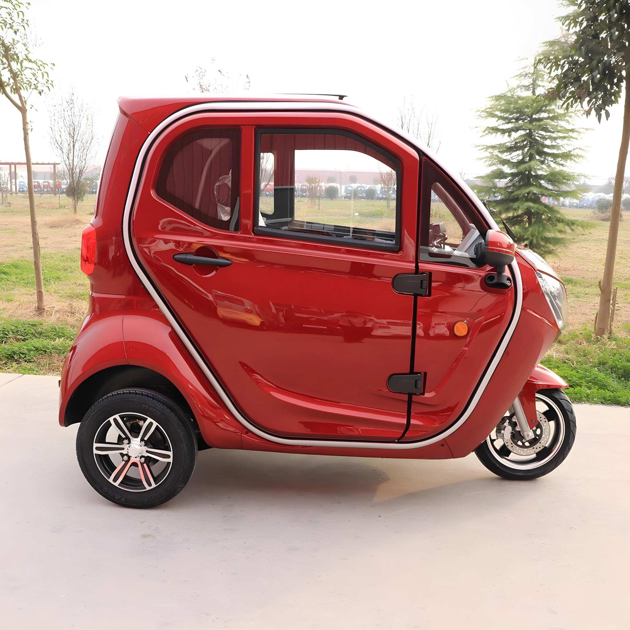 Ein roter EQ-Mobil Kabinenroller Lima Q3 Li 45/25 km/h, Lithium-Akku, steht im Freien auf einer gepflasterten Fläche umgeben von Gras und Bäumen unter einem bewölkten Himmel.