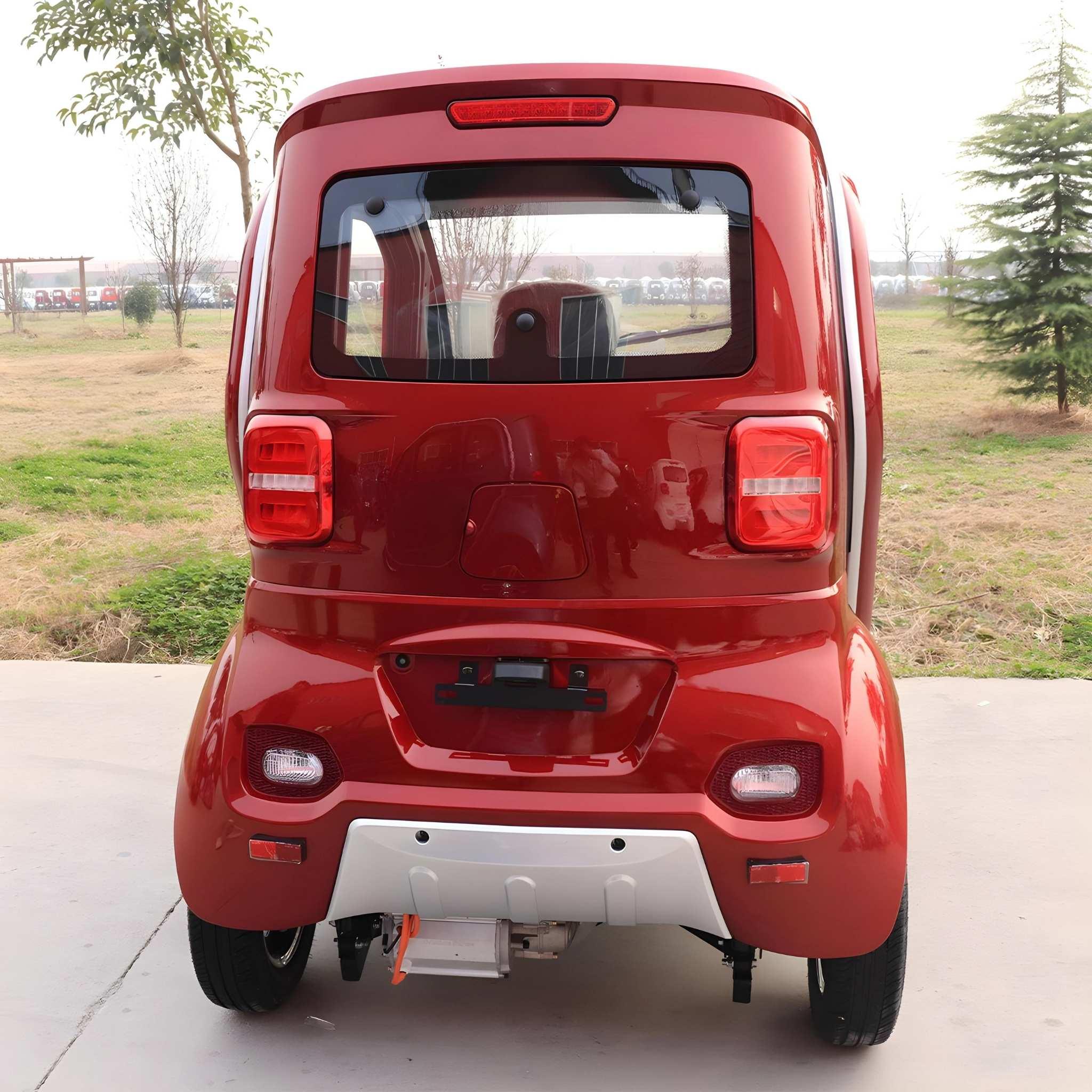 Ein roter EQ-Mobil Kabinenroller Lima Q3 Li 45 / 25 km/h mit einem Lithium-Akku wird von hinten gezeigt, geparkt auf Beton mit Gras und Bäumen unter einem bewölkten Himmel.