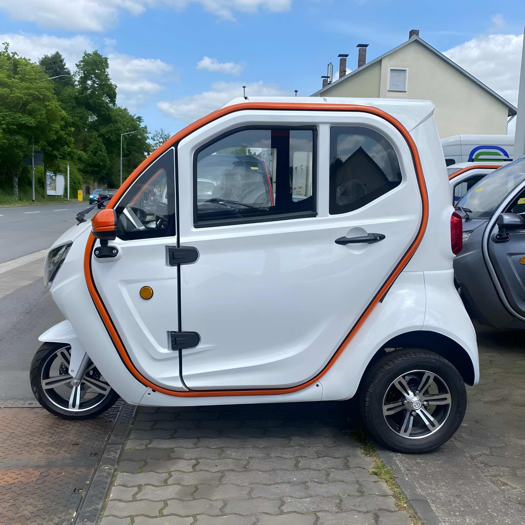 Ein kompakter, weißer EQ-Mobil Kabinenroller Lima Q3 Li 45 mit orangefarbener Zierleiste ist auf dem Bürgersteig in der Nähe einer Straße, von Häusern und Bäumen unter einem teilweise bewölkten Himmel geparkt. Dieses aktuelle Modell ist mit einer Lithium-Batterie ausgestattet und erreicht eine Geschwindigkeit von 25-45 km/h.