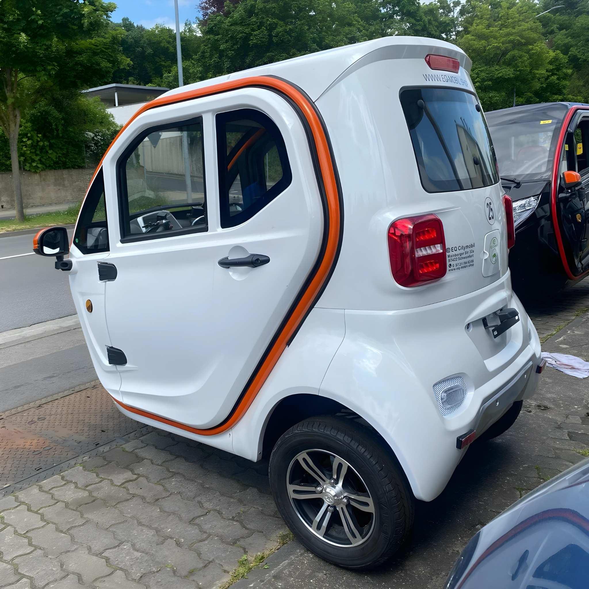 Ein kompakter weißer EQ-Mobil Kabinenroller Lima Q3 Li 45/25 km/h mit orangefarbener Verkleidung und einer Lithiumbatterie ist auf dem Bürgersteig neben einem anderen Fahrzeug, Bäumen und einer im Hintergrund sichtbaren Straße geparkt.