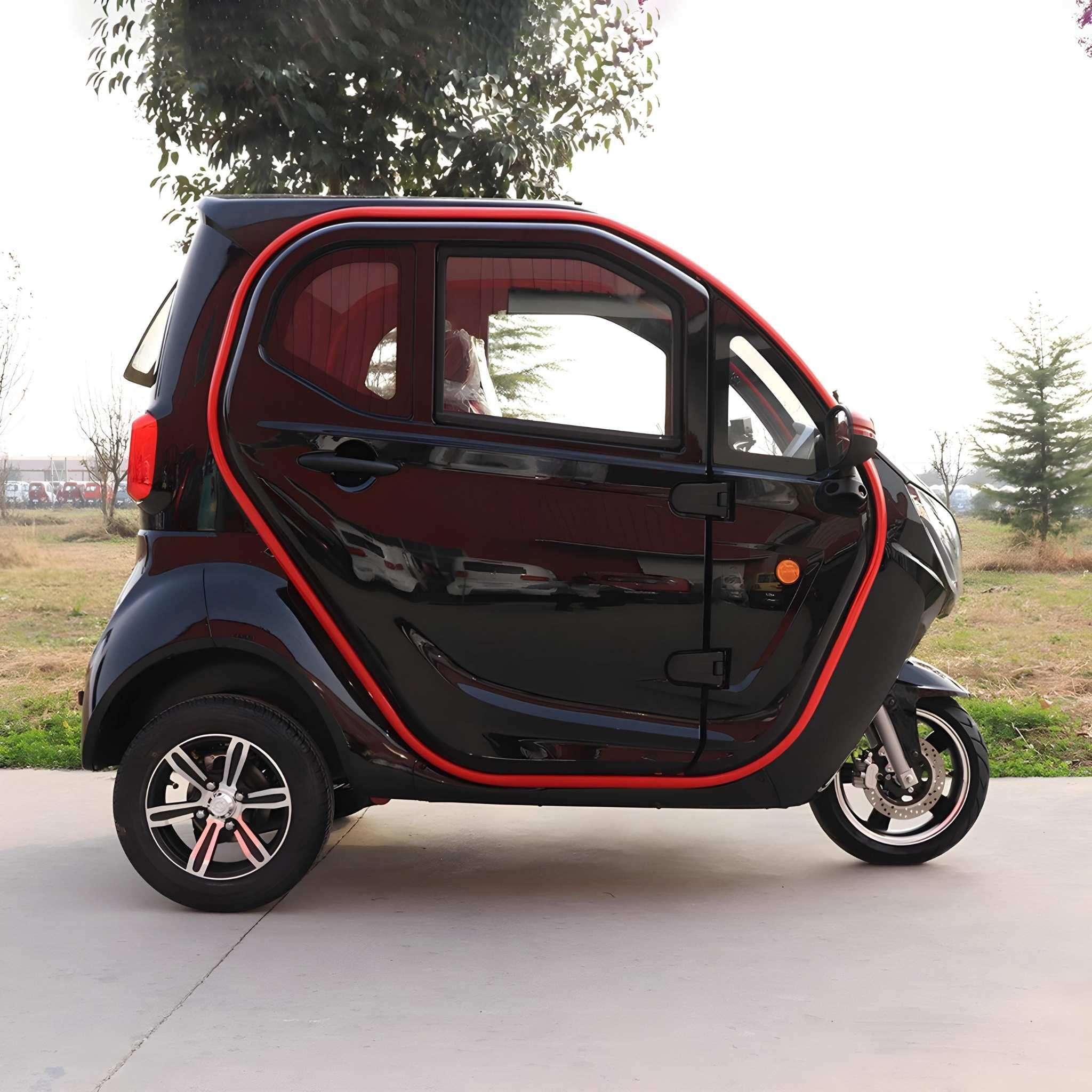 Ein kompakter, schwarz-roter EQ-Mobil Kabinenroller Lima Q3 Li 45/25 km/h mit Lithium-Akku (aktuelles Modell) ist auf einem Gehweg neben einer Wiese und Bäumen geparkt.