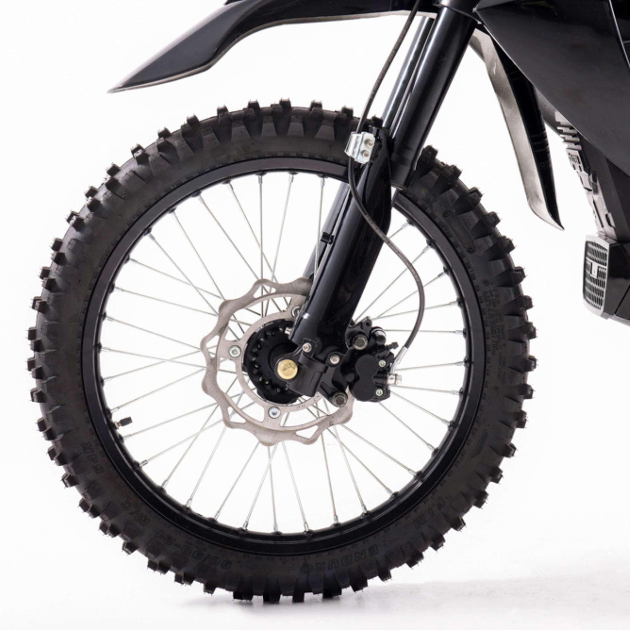 Die Nahaufnahme des Vorderrads des Tinbot Esum ES1 45 km/h Enduro mit Stollenreifen, Scheibenbremse und Federgabel hebt das robuste Design von Tinbot vor einem schlichten weißen Hintergrund hervor.