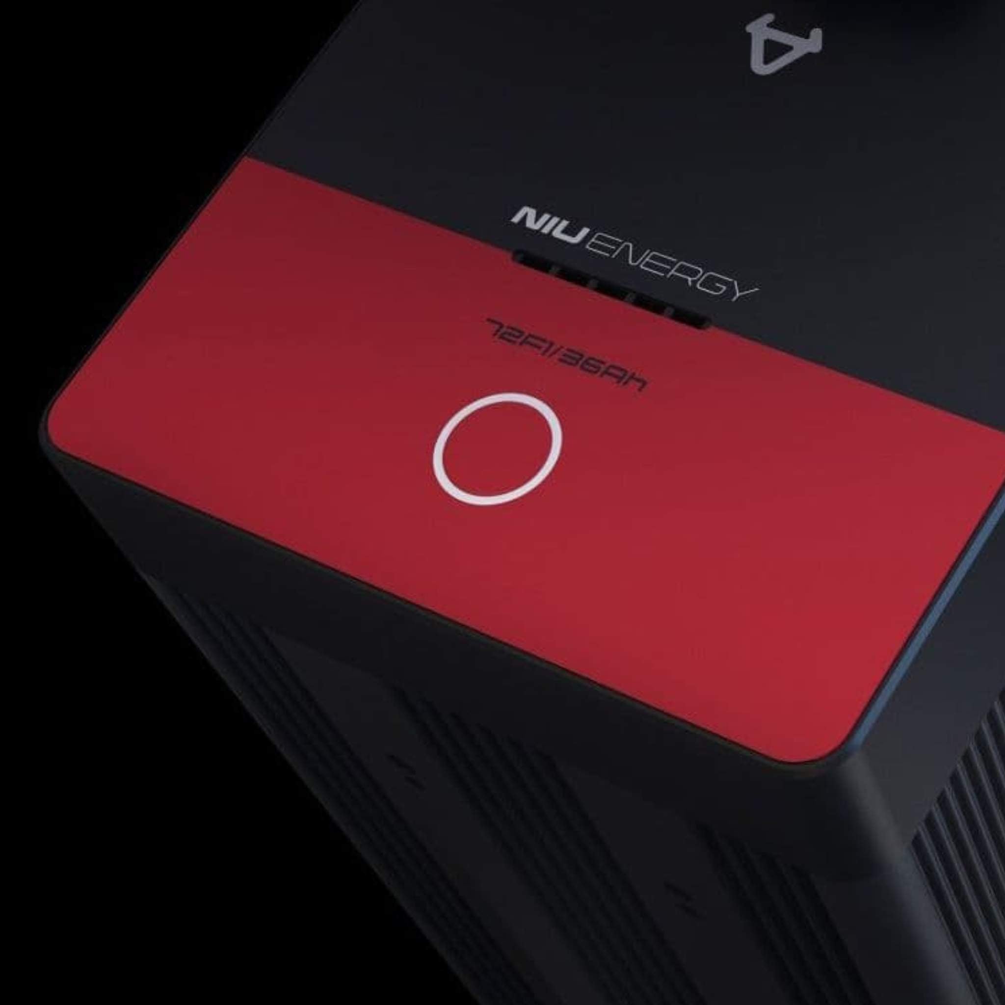 Nahaufnahme eines rechteckigen Geräts NIU ENERGY 48V 26Ah mit rotem Deckel und weißem Knopf, abgebildet auf Schwarz - ein wesentliches Teil für das NIU Elektromotorrad RQI Sport 110 km/h von NIU.