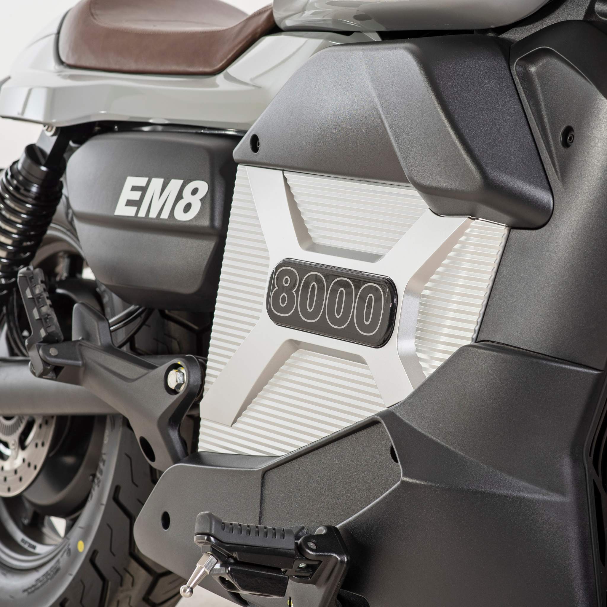 Nahaufnahme des E.F.O. Elektro Motorrad EM8 120 km/h - Aktionspreis! mit EM8 an der Seite, 8000 auf einer Metallplatte und Details des Hinterrads, der Fußraste und der Federung.