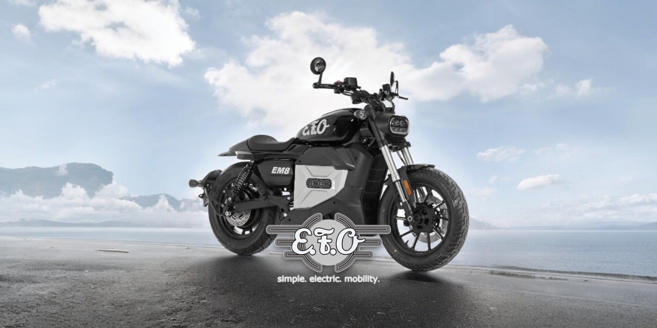 A SONS OF ELECTRICITY Angebot AG-20250025 E-Motorrad ist auf einer nassen Küstenstraße geparkt, mit Bergen und einem bewölkten blauen Himmel im Hintergrund. Das E&C-Logo und der Schriftzug simple. electric. mobility. überlagern das Bild.