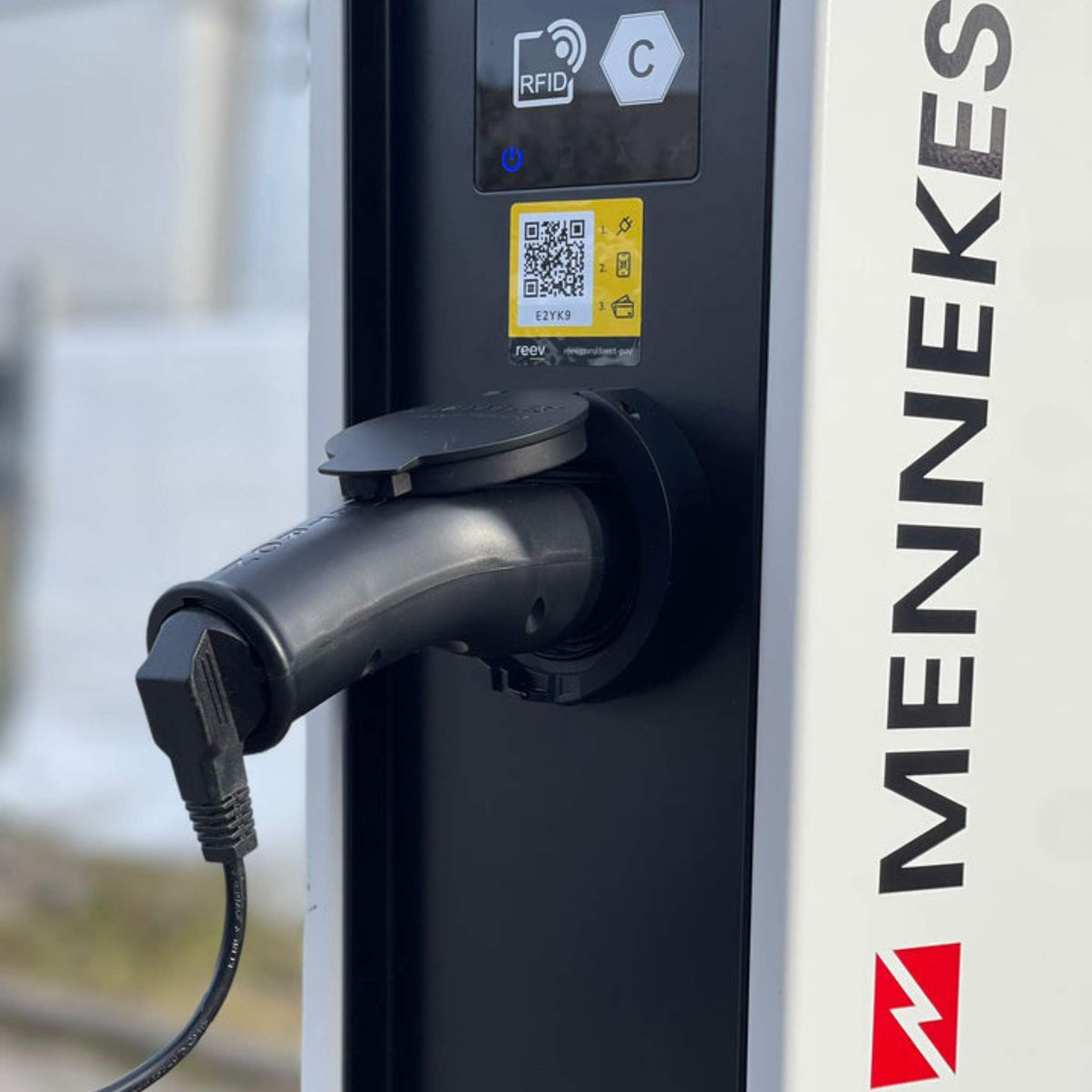 Eine Nahaufnahme des VMOTO TYP2 Adapter für Schuko Stecker, die zuverlässige Ladelösung für dein Elektro Motorrad, E-Chopper, E-Roller & E-Scooter, mit angeschlossenem Kabel. Das Panel zeigt diverse Symbole; Hintergrund bleibt unscharf.