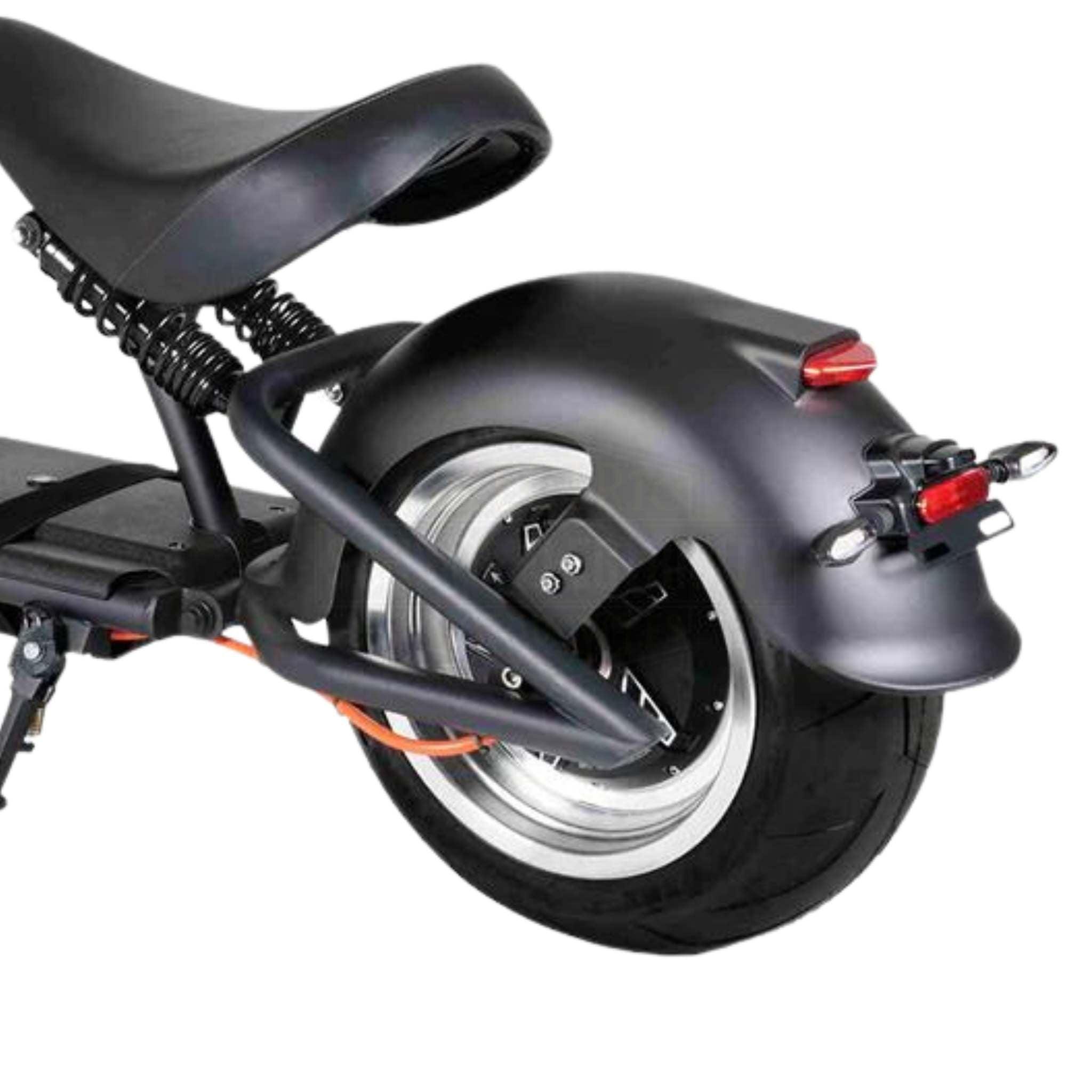 Nahaufnahme des Hecks des Mangosteen E-Chopper M1P - 30 Ah Akku 45 km/h, die den Sitz, den hinteren Kotflügel, den breiten Reifen, die Aufhängungsfedern, das Rücklicht und den Nummernschildhalter vor einem weißen Hintergrund zeigt.