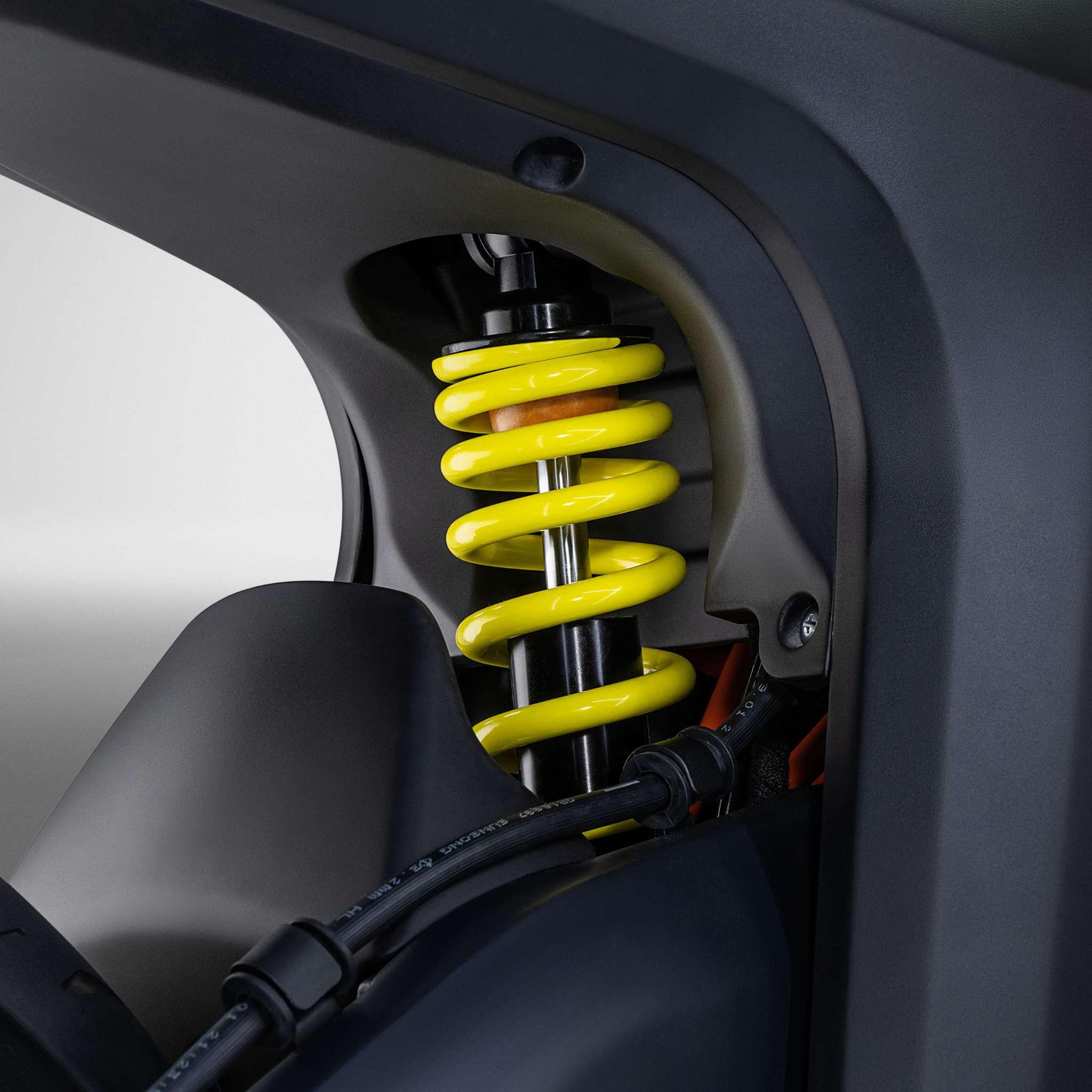 Nahaufnahme einer leuchtend gelben Schraubenfeder und eines Stoßdämpfers im Inneren des dunkelgrauen E-Motorrad Naxeon I AM. PRO-Rahmen von NAXEON, der sein fortschrittliches, für die Turbo Boost-Performance entwickeltes Federungssystem vorstellt.