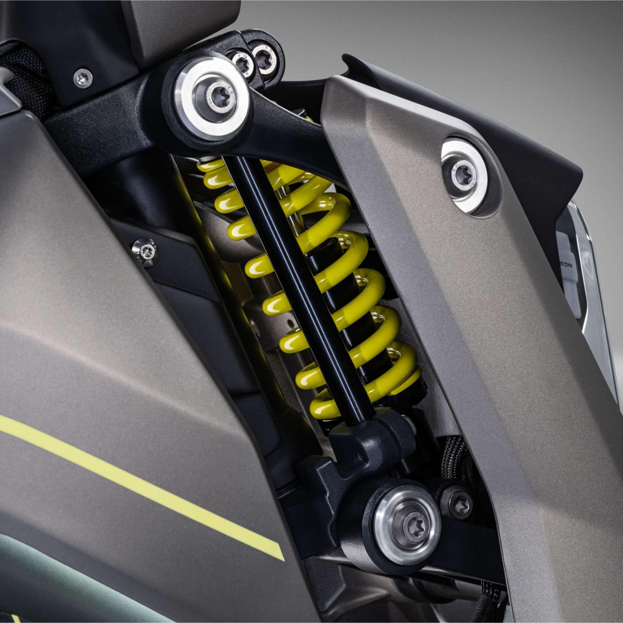 Nahaufnahme einer gelben Schraubenfederaufhängung am NAXEON E-Motorrad Naxeon I AM. PRO (Kopie), mit detaillierten mechanischen Komponenten und mattgrau-schwarzen Karosserieteilen.