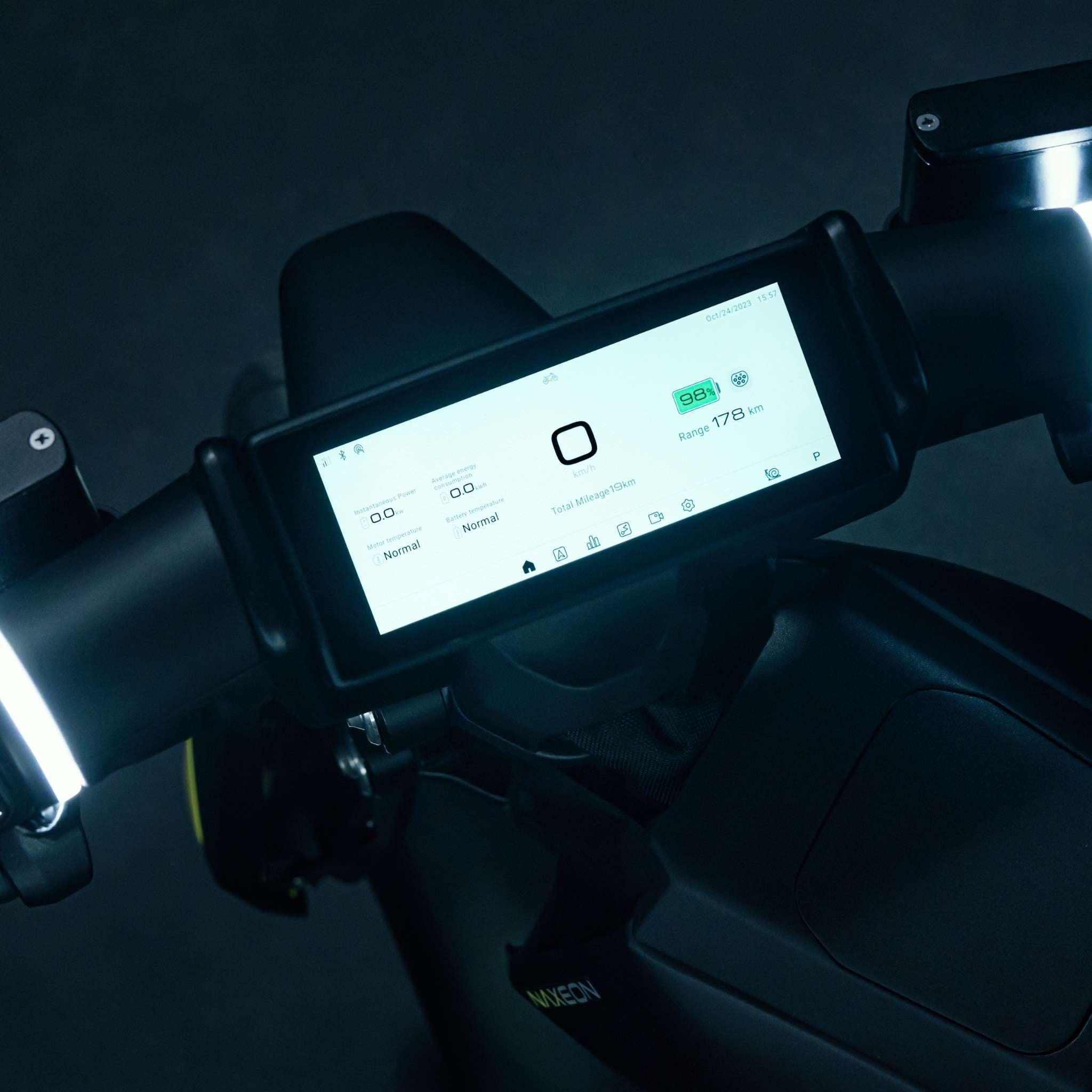 Nahaufnahme des NAXEON E-Motorrad Naxeon I AM. PRO zeigt Geschwindigkeit, Akkustand, Fahrmodus, Turbo Boost-Status und Reichweite an. Der Lenker mit beleuchteten Griffen ist teilweise zu sehen.