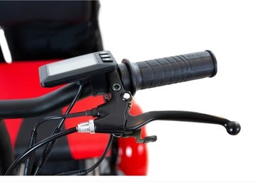 Nahaufnahme eines SONS OF ELECTRICITY Mobot Krankenfahrstuhl / Seniorenmobil 15 km/h Lenkers, mit schwarzem Gummigriff, elektronischem Display, Bremshebel und Kabeln vor einem rot-schwarzen unscharfen Hintergrund.