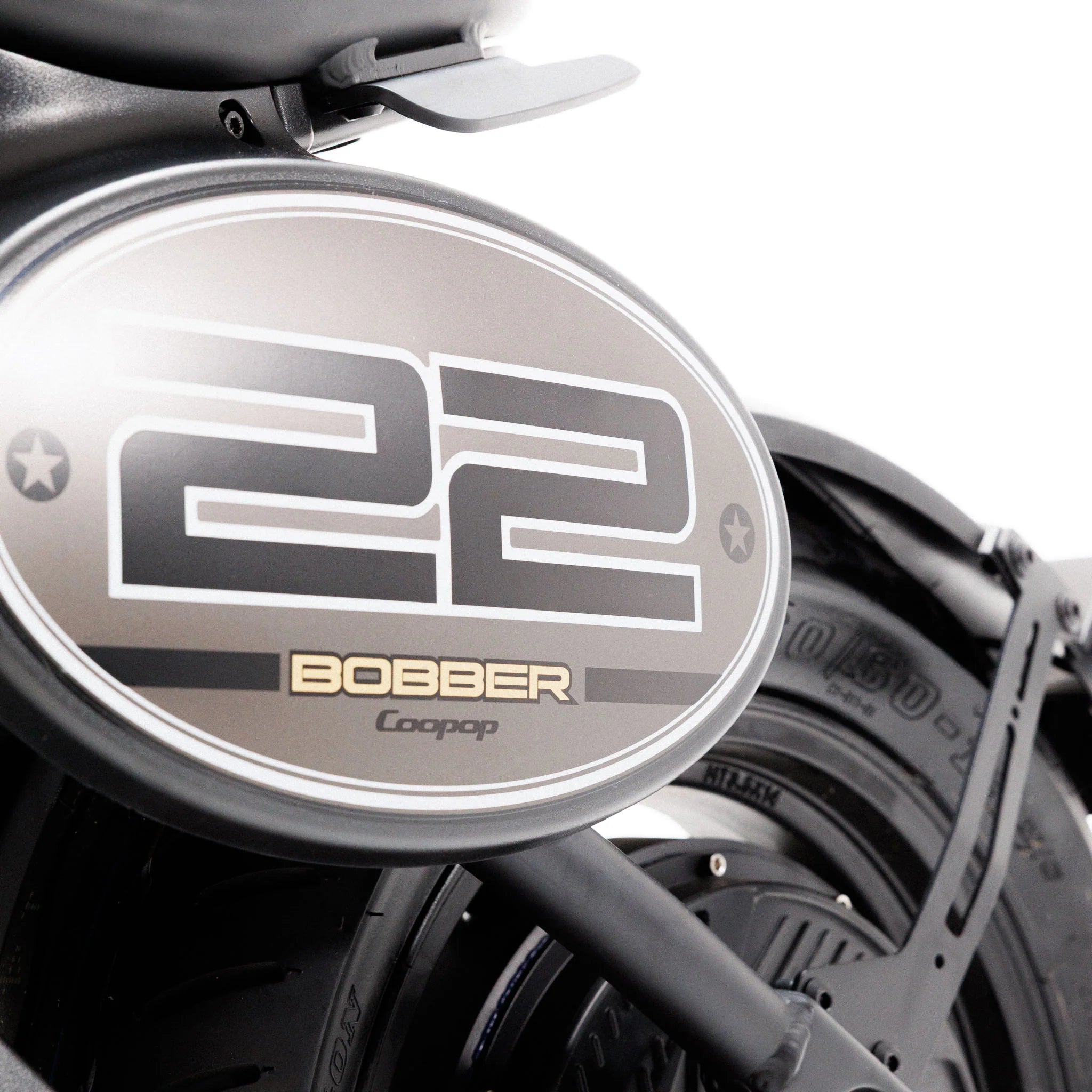 Nahaufnahme des Hinterrads und des Kotflügels des Coopop Bobber mit einem ovalen 22er-Kennzeichen sowie den Aufdrucken „BOBBER“ und „Coopop“. Das Reifenprofil und der Rahmen des E-Choppers unterstreichen den geräuschlosen, leistungsstarken Elektroantrieb mit 45 km/h (L1e).