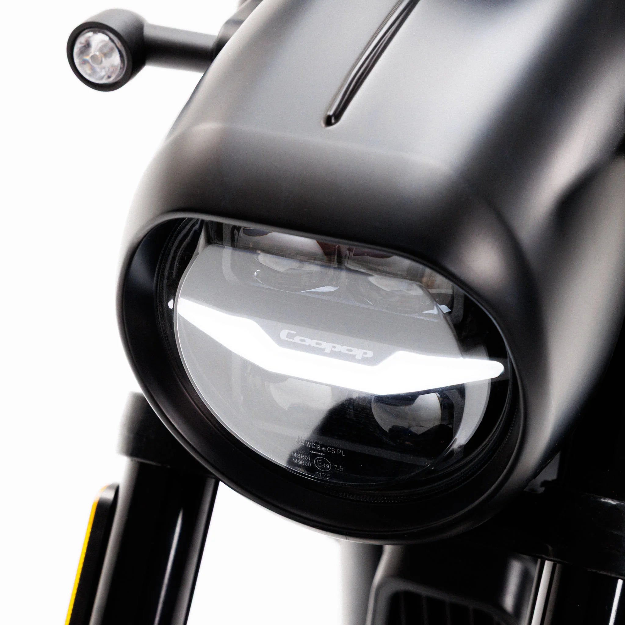 Nahaufnahme des kantigen LED-Scheinwerfers des Coopop Bobber E-Chopper mit dezentem „Coopop“-Logo, der seinen innovativen Elektroantrieb zur Geltung bringt; der stärkste E-Chopper seiner Klasse mit 45 km/h und einem geräuschlosen, leistungsstarken Design.