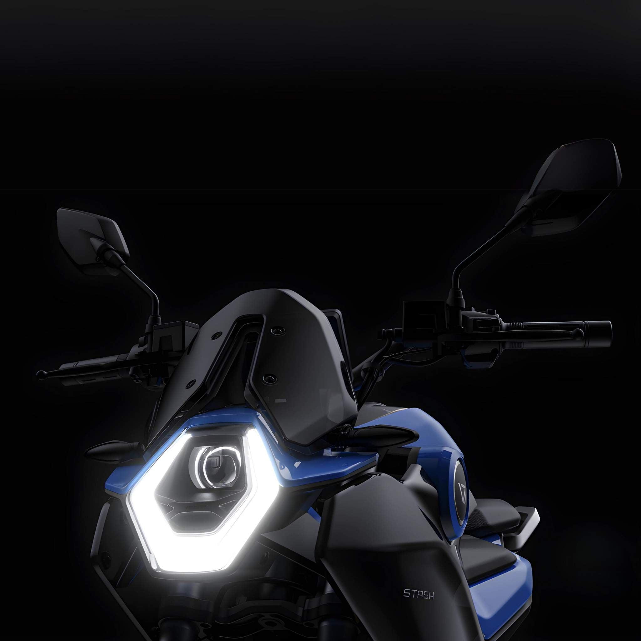 Nahaufnahme der Vorderseite des VMOTO Elektro Motorrad Stash 120 km/h, die den hellen sechseckigen LED-Scheinwerfer, das blau-schwarze Design, die Rückspiegel und den Lenker vor einem dunklen Hintergrund zeigt.