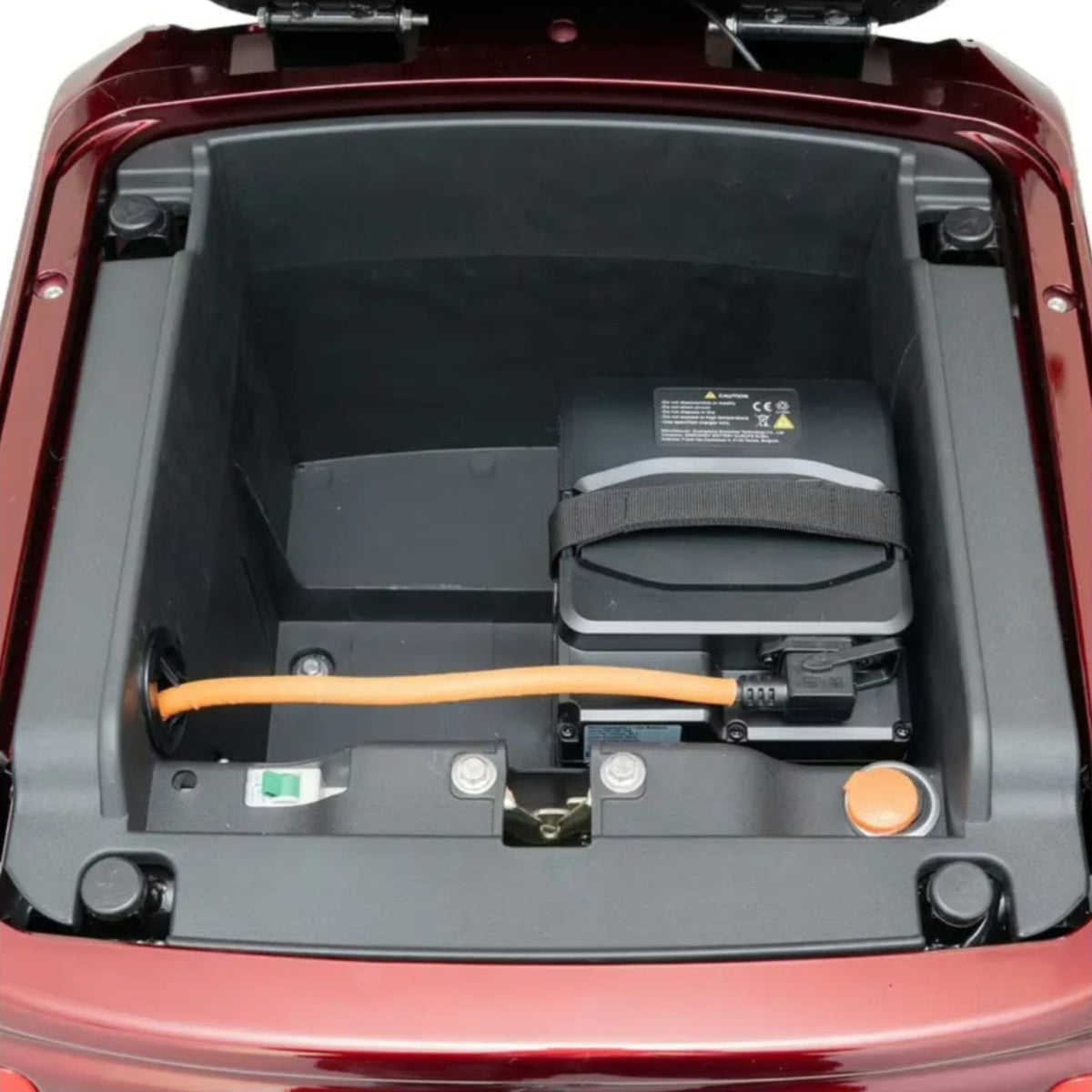 Geöffneter Kofferraum eines TRINITY Atlas Premium 1800 | Seniorenmobil 25 km/h von Trinity, in dem eine Batterie, ein orangefarbenes Ladekabel und verschiedene Anschlüsse ordentlich in einem übersichtlichen Fach unter der Motorhaube angeordnet sind – ein Beleg für die fortschrittliche Technik dieses Trinity-Fahrzeugs.