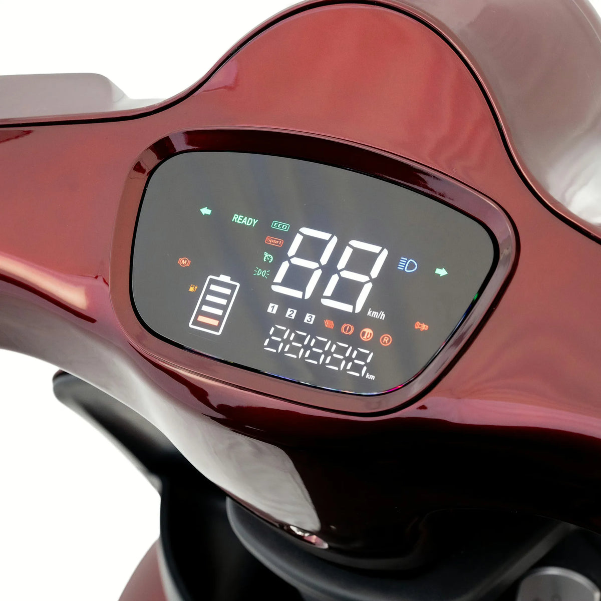Nahaufnahme des digitalen Armaturenbretts des Elektrorollers „Trinity TRINITY Atlas Premium 1800 | Seniorenmobil 25 km/h“, auf dem Geschwindigkeit, Akkustand und verschiedene Kontrollleuchten auf einem glänzend roten Panel angezeigt werden – ein Beispiel für das raffinierte Design der Trinity-Elektromobile.
