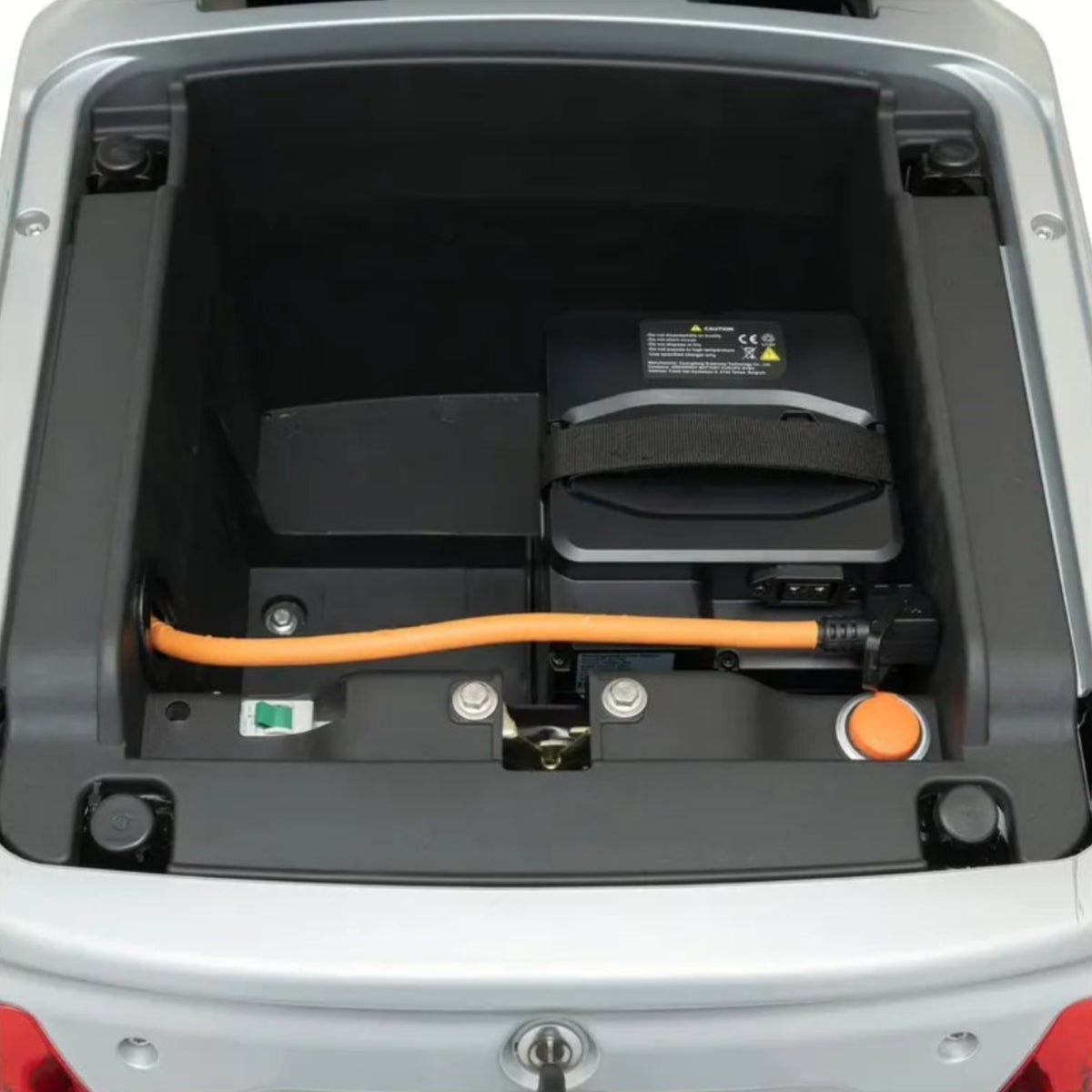 Eine Nahaufnahme des offenen Batteriefachs eines Trinity Seniorenmobils (25 km/h) mit dem TRINITY Atlas Premium 1800-Akku, einem orangefarbenen Stromkabel und verschiedenen Steckverbindern in einem grauen Gehäuse – ein Beispiel für die innovative Technik von Trinity.
