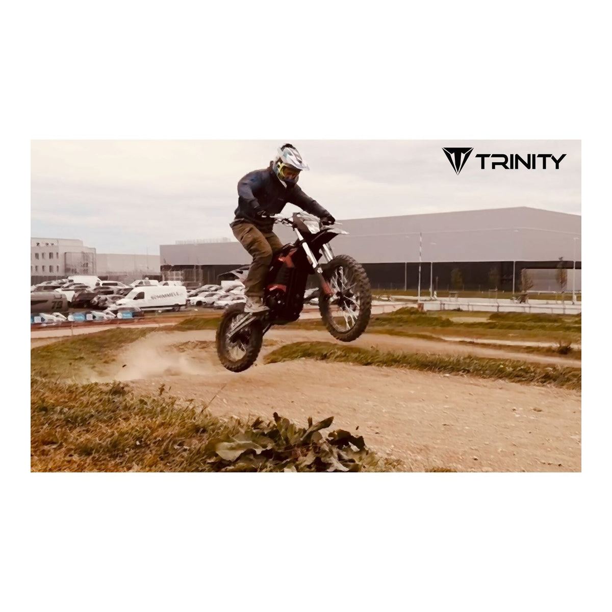 Eine Person, die einen Helm und Schutzkleidung trägt, fährt mit einem Motorrad vom Typ TRINITY Panthera II: E-Enduro 125 km/h mit 4-Gang auf einer unbefestigten Strecke.