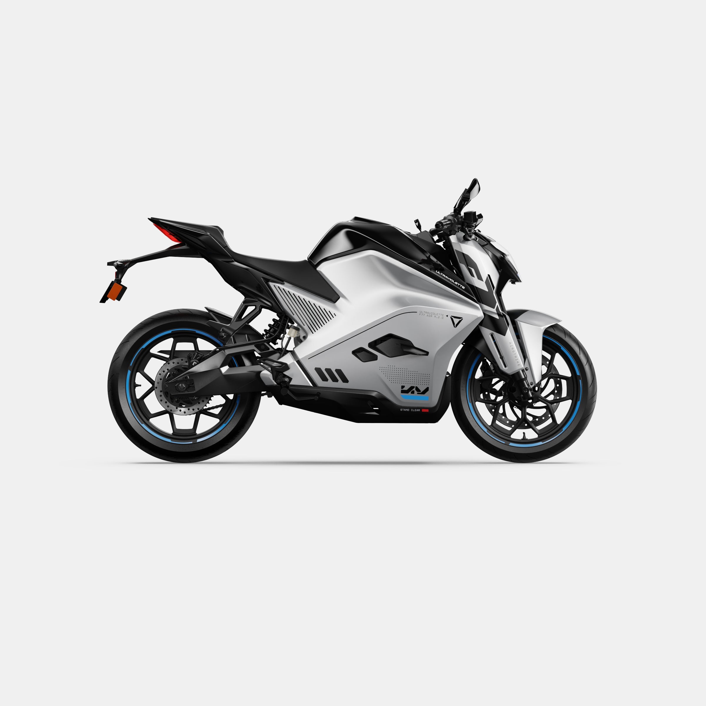 Das Ultraviolette F77 Mach 2 Recon - Performance Elektromotorrad von Ultraviolette ist im Profil zu sehen. Es zeichnet sich durch ein elegantes silbernes Finish, blau akzentuierte Räder und ein kantiges, minimalistisches Design vor einem weißen Hintergrund aus.