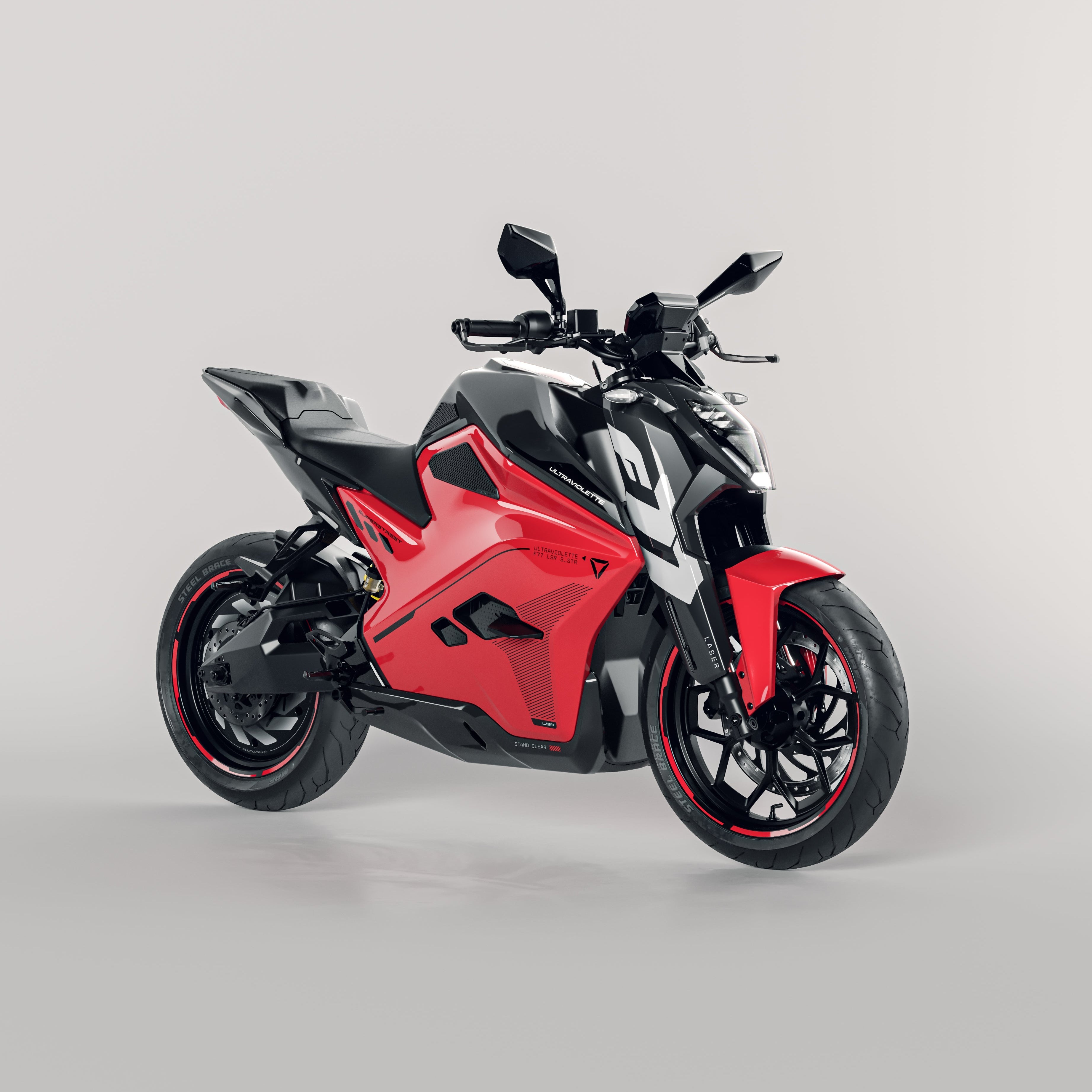 Ein schnittiges rot-schwarzes Ultraviolette F77 Superstreet Recon Elektro-Sportmotorrad von Ultraviolette mit scharfem, kantigem Design, großen Reifen und Seitenspiegeln wird vor einem schlichten hellen Hintergrund präsentiert.