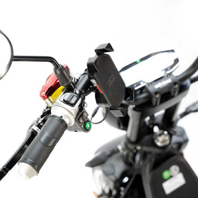 Nahaufnahme eines City Twister E-Choppers: CityTwister 3.0-Lenker mit dem neuen TFT-Multimedia-Spiegel-Display, Smartphone-Halterung, Bedientasten, Spiegel und Gasgriff. Der weiße, sanft unscharfe Hintergrund unterstreicht das moderne Design dieses Originalmodells von City Twister, das in Versionen mit 25 oder 45 km/h erhältlich ist.