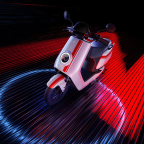 Der NIU Elektroroller E-Scooter NQI GTS (2024 Upgrade) 45 km/h in Weiß und Rot besticht durch seinen runden Scheinwerfer, der von leuchtend roten und blauen Lichtstreifen umrahmt wird, die sein modernes Design und seinen Sinn für Geschwindigkeit unterstreichen.