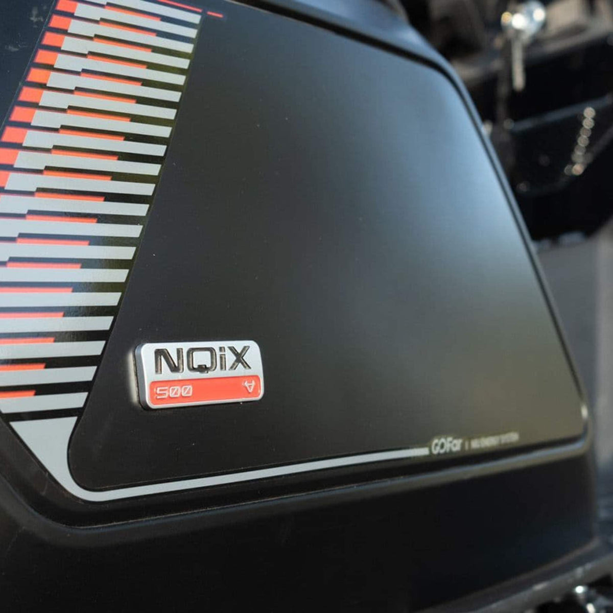 Nahaufnahme einer schwarzen Fahrzeugverkleidung mit NIU-Logo und NQiX 500-Emblemen sowie dem GOFar-Logo und einem Muster aus roten, weißen und grauen Streifen auf der linken Seite – die die modernen Designelemente des NIU NQiX 500 Elektrorollers hervorheben (Modell 2025) | 100 km/h Sonderpreis.