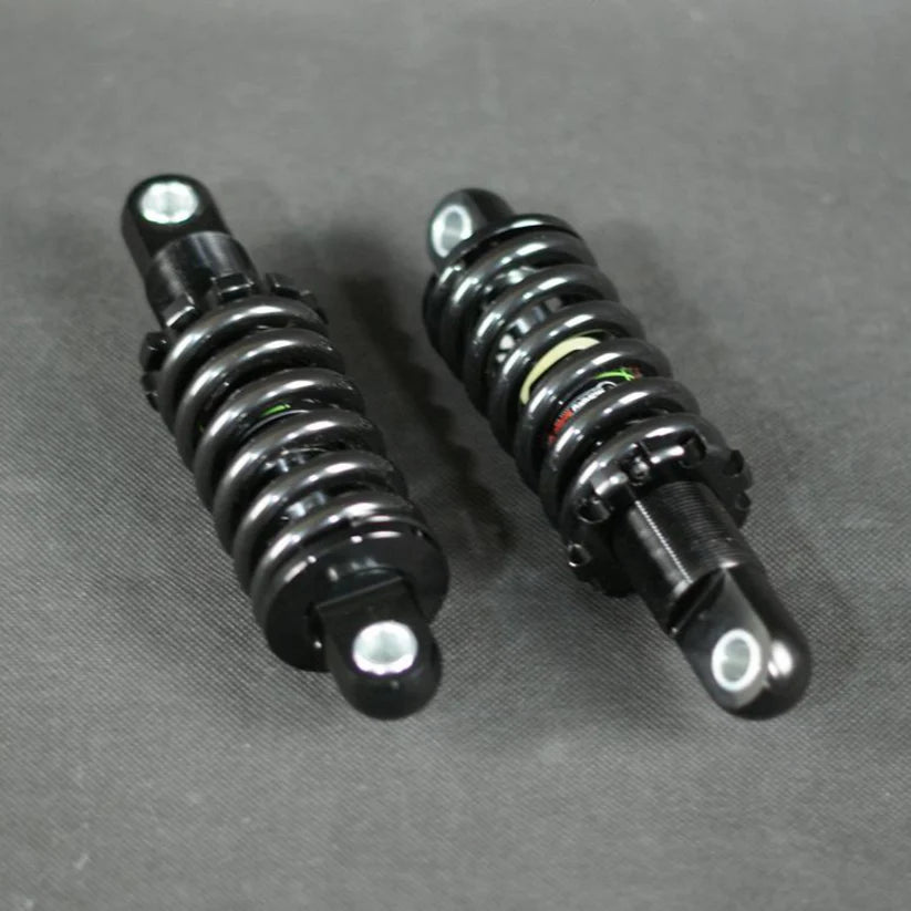 Zwei schwarze Hydraulische Stoßdämpfer hinten von Wandler liegen parallel auf einer dunkelgrauen Fläche, Metallbefestigungslöcher an beiden Enden sichtbar. Dieses Upgrade für Wandler K/E und A/E sorgt für zuverlässige Leistung und Langlebigkeit.