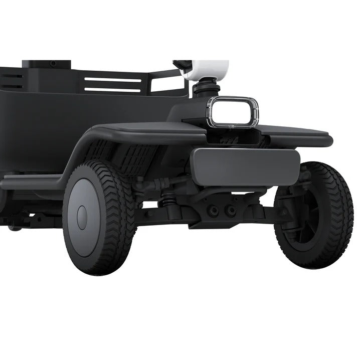 Nahaufnahme der Vorderräder und unteren Karosserie des WHILL Model R 4-Rad von Whill - einem wendigen Mobilitätsroller für Senioren (6 km/h), schnell zerlegbar - mit Fokus auf Federung, Reifen und Rahmen.