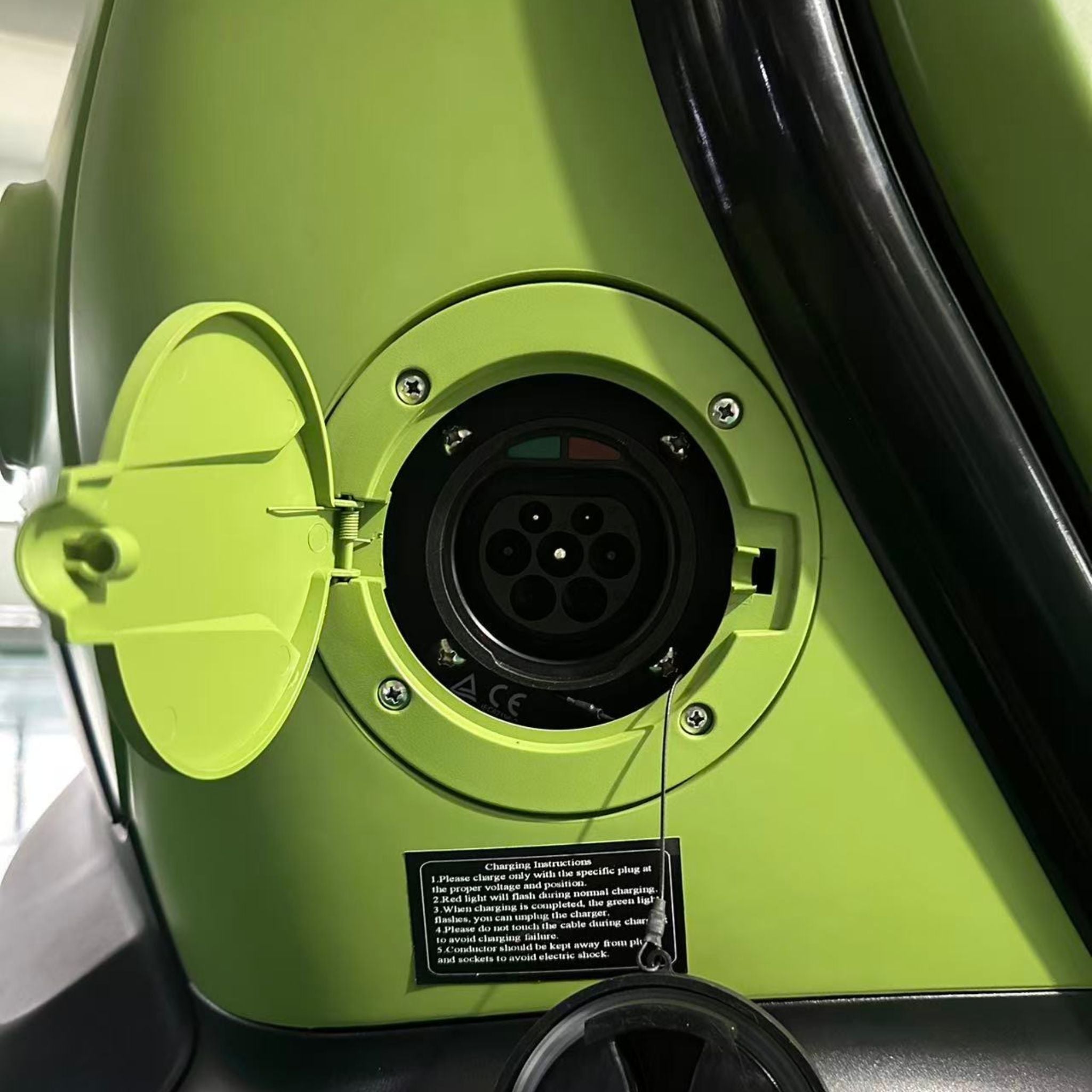 Nahaufnahme des offenen Ladeanschlusses an einem City Twister Luqi EV300 Pro Kabinenroller Facelift 2026 Miniauto. Hervorzuheben sind der kreisförmige mehrpolige Anschluss und das Etikett mit der Gebrauchsanweisung unterhalb des Anschlusses.