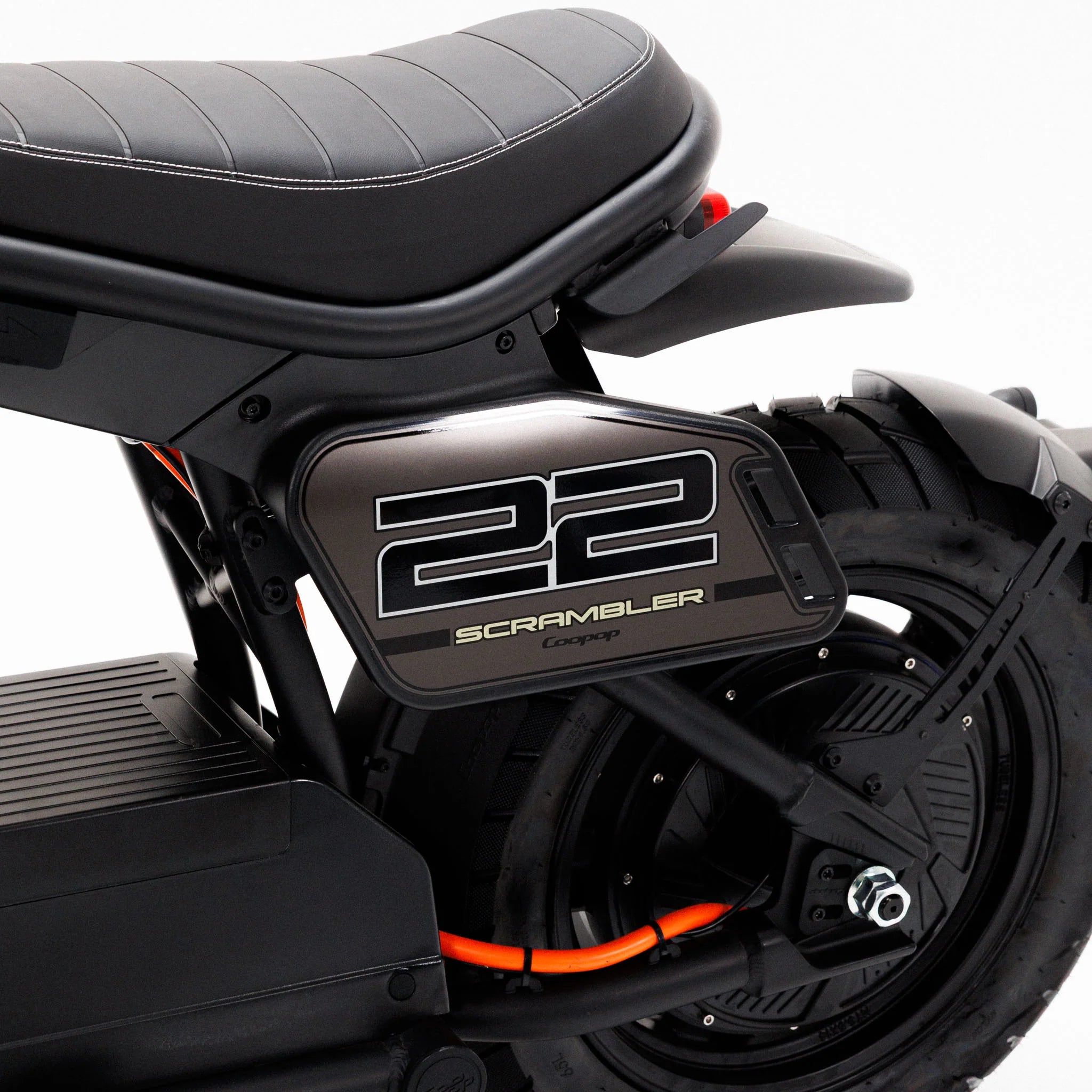 Nahaufnahme des Sitzes und des Hinterrads eines Coopop Scrambler 45 km/h E-Rollers mit einer Seitenverkleidung mit der Aufschrift „22 SCRAMBLER Concept“ in kräftigem Weiß. Das Design besticht durch orangefarbene und metallische Akzente, die den Charakter dieses Offroad-E-Scooters mit einer Spitzenleistung von 8 kW widerspiegeln.