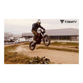 Eine Person, die einen Helm und Schutzkleidung trägt, fährt mit einem Motorrad vom Typ TRINITY Panthera II: E-Enduro 125 km/h mit 4-Gang auf einer unbefestigten Strecke.