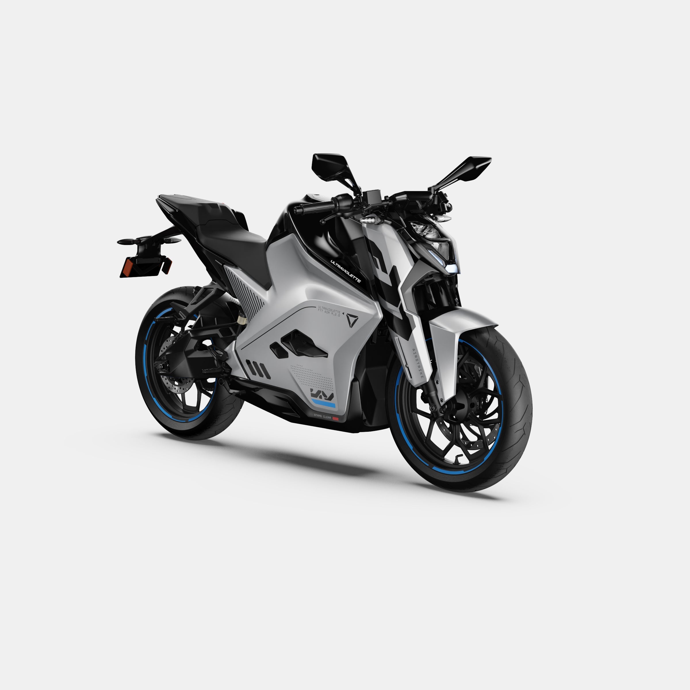 Die Ultraviolette F77 Mach 2 Recon - ein silbernes Hochleistungs-Elektromotorrad von Ultraviolette mit aggressivem Styling, blauen Felgenakzenten und einer kantigen Karosserie - wird auf einem schlichten weißen Hintergrund in einer Dreiviertelansicht der Front gezeigt.