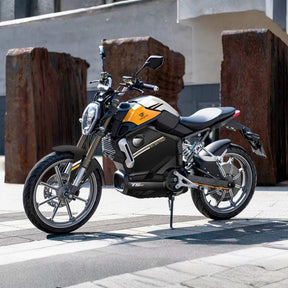 Der leistungsstarke VMOTO TSX 72V Elektroroller im Motorrad-Design steht auf einem modernen Stadt-Bürgersteig, umgeben von großen rostigen Metallskulpturen und zeitgenössischen Gebäuden.